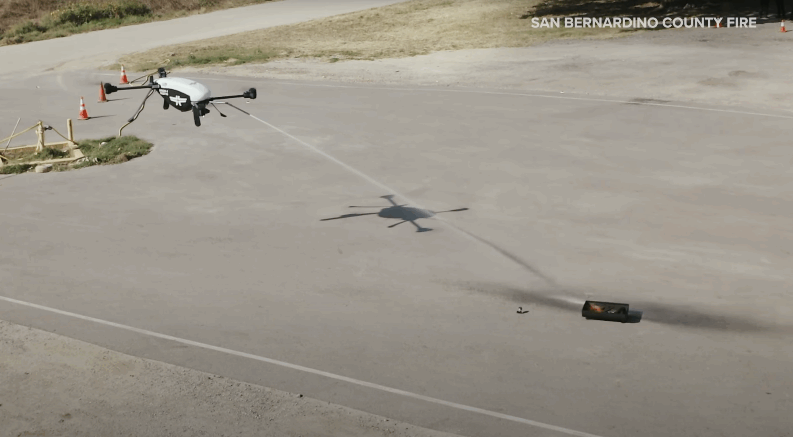 A firefighting drone sprays water onto a small controlled fire during a demonstration by San Bernardino County Fire.