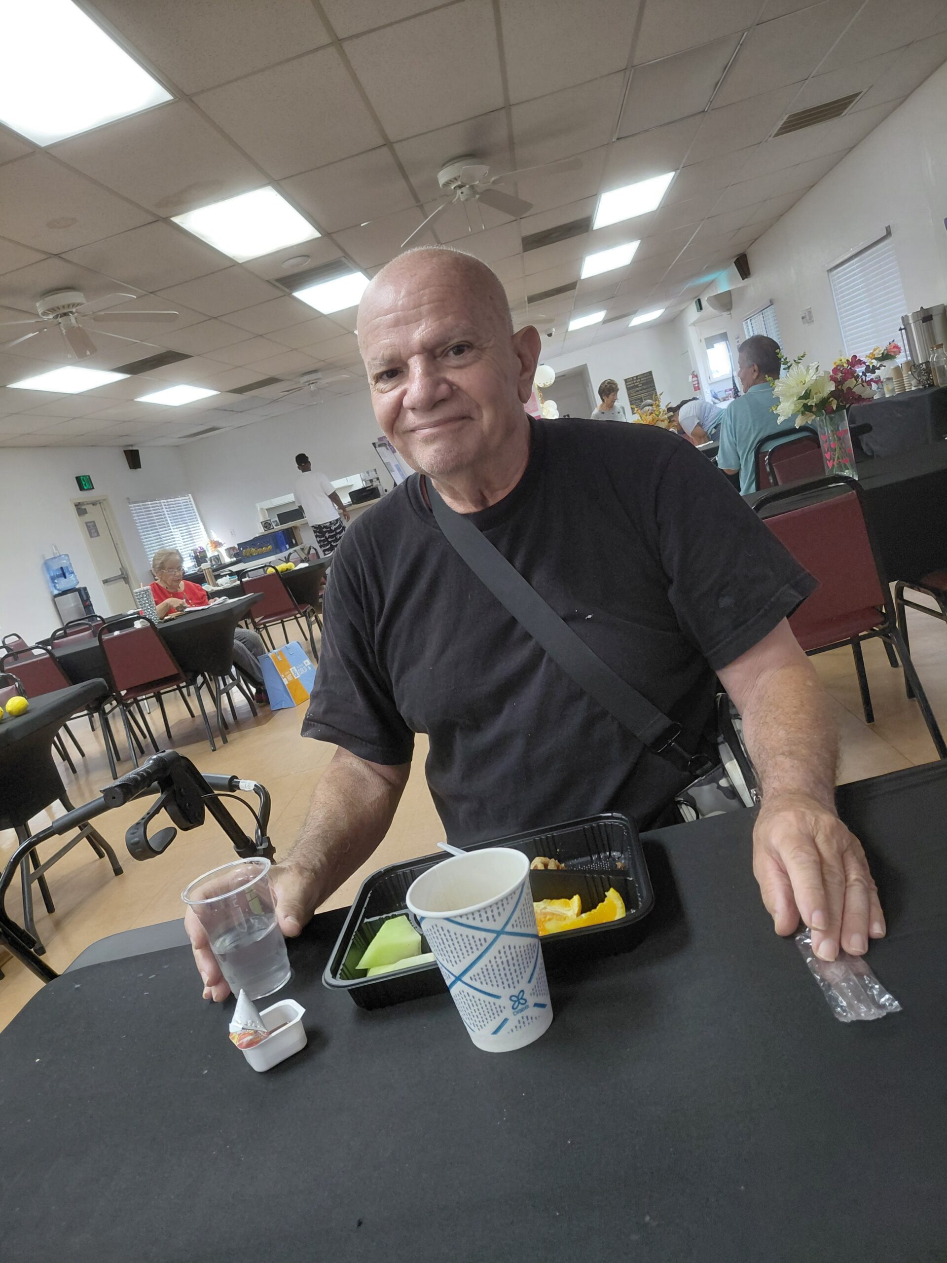 Senior man seated at a table inside the Senior Center of Adelanto, enjoying a meal.