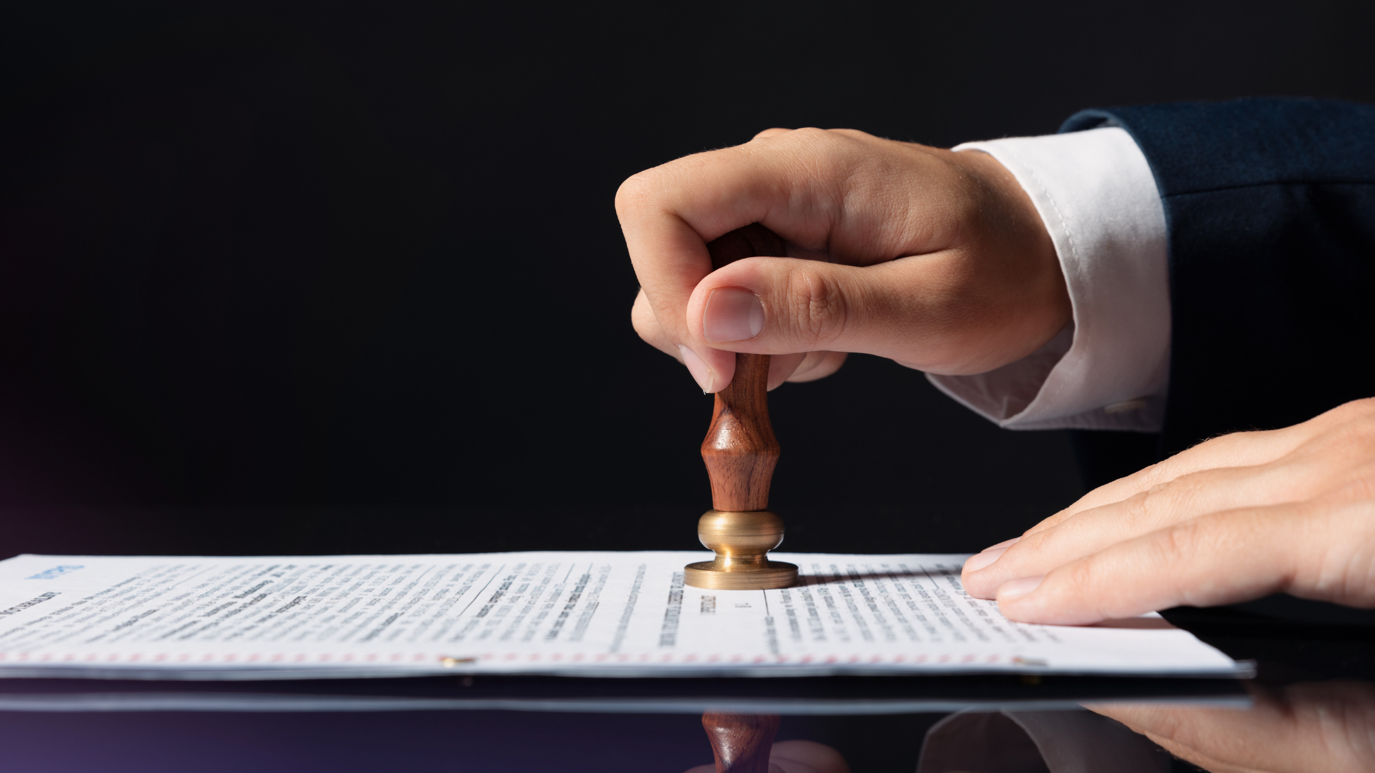 Close-up image of a person in formal attire stamping an official document with a wooden seal.