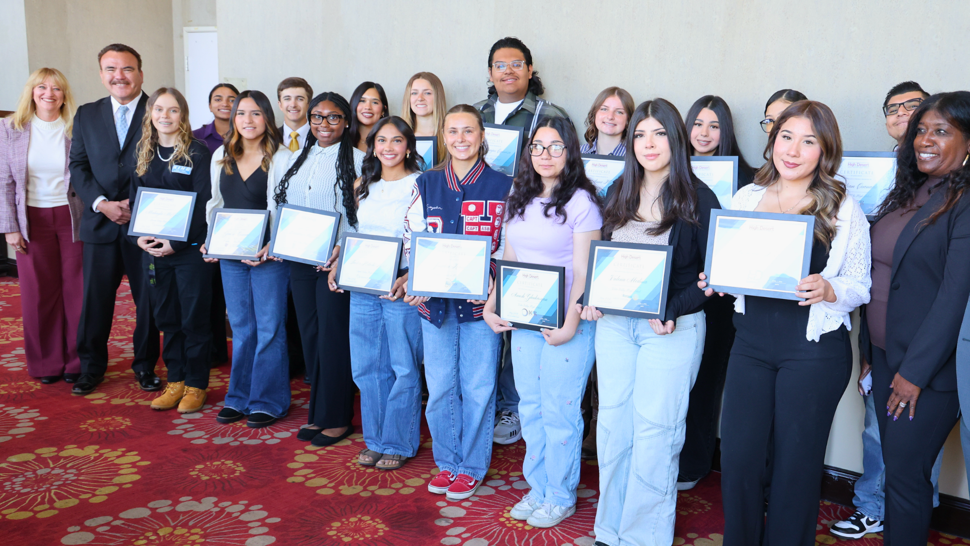A group of students and community members stand together holding scholarship award certificates at the State of Education event.